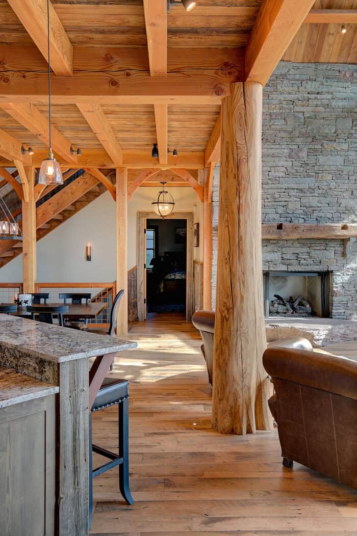 A natural timber frame home with exposed wood beams and stone accents, perfect for a mountain or lak.
