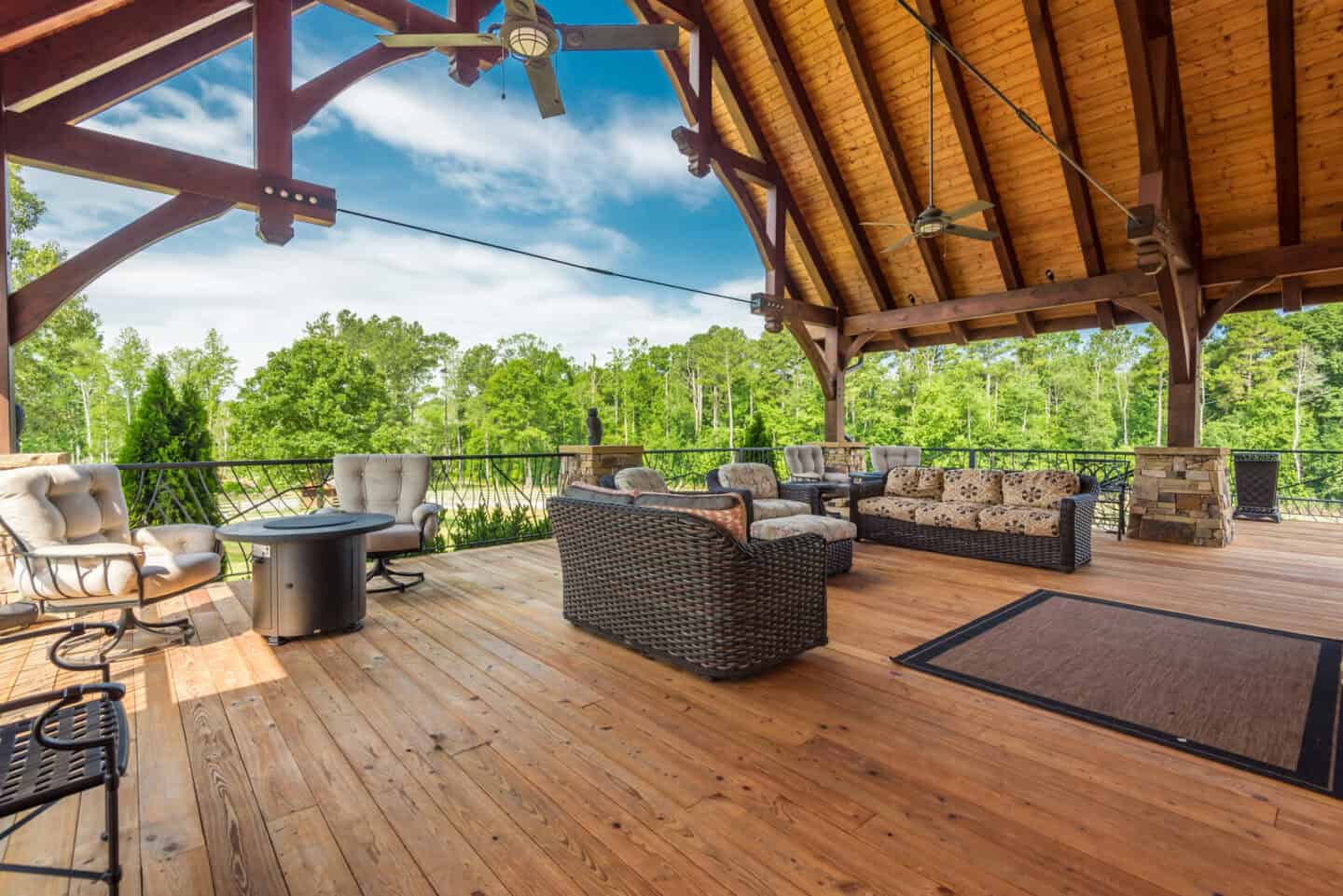 Elegant natural log cabin outdoor pavilion with timber frame architecture set in lush green mountain.